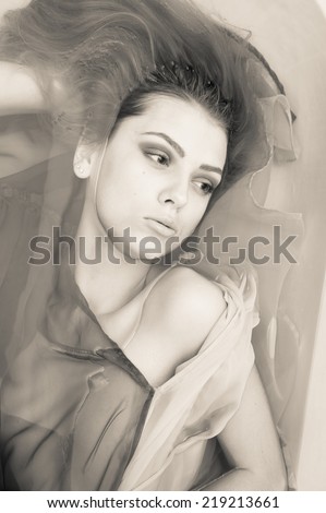 sensual spa: black and white portrait of elegant girl with silk skin, excellent blond hair laying in clear water on copy space background