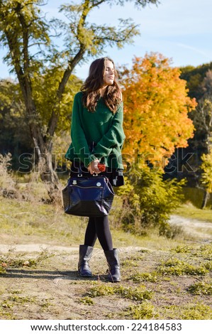 portrait of beautiful young lady with bag standing on autumn countryside road and enjoying sunshine on sunny outdoors copy space background