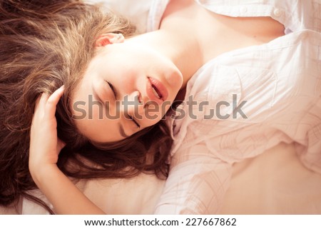 sleeping beauty: closeup portrait of young beautiful glamor woman in white shirt lying on the bed eyes closed