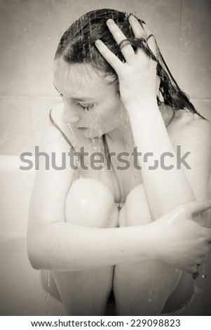 black and white portrait of looking depressed and crying emotional blond young beautiful lady relaxing in bath shower