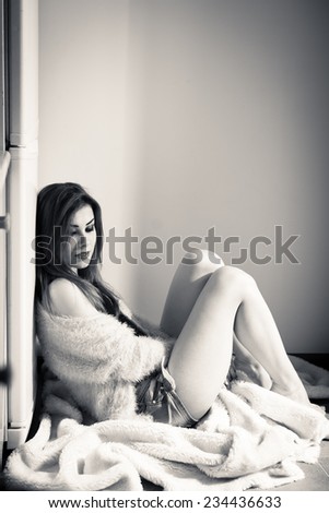 beautiful sad or calm young woman sitting relaxing back to fridge on copy space background, black and white portrait