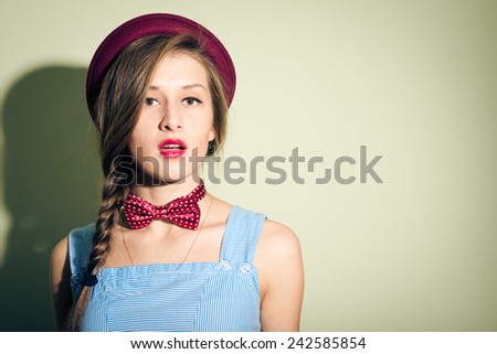 pretty girl in red hat and bow tie looks surprised
