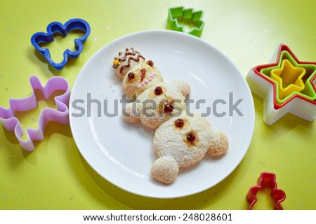 image of snowman on white plate with colorful molds on green background