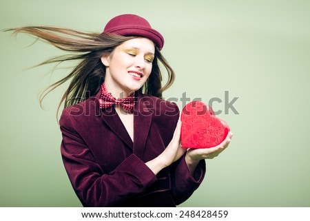 Portrait of romantic beautiful girl with red present box in the form of heart