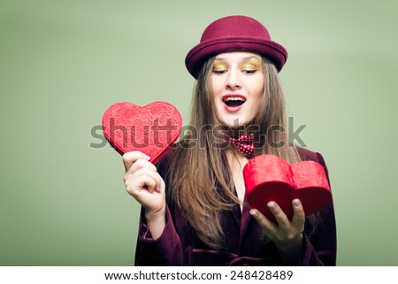 Portrait of romantic beautiful young lady opening red present box in the form of heart