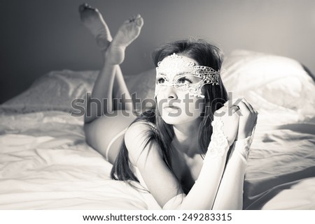 Black and white picture of beautiful young lady in lingerie relaxing in bed