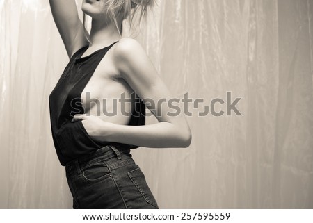 Black and white portrait of sexy beautiful young lady in black dress on light curtain background