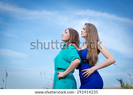 2 best female friends looking up at blue sky on summer outdoors copy space background