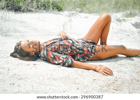 Portrait of beautiful sexy young woman laying on the sand ground on sunshine outdoors background