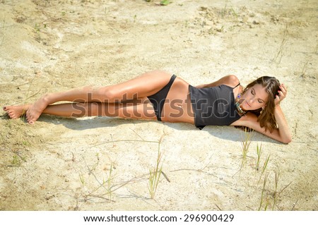 Portrait of beautiful sexy girl lying on the sand ground on sunshine outdoors background