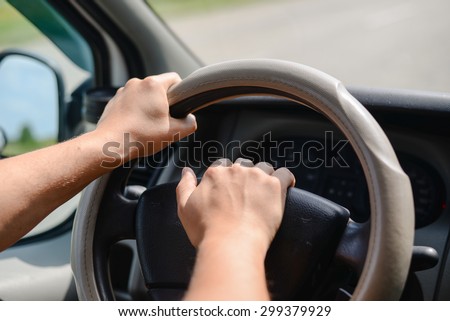Man\'s hands holding a wheel of a car and beeping a horn