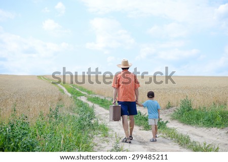 Dad with suitcase holding his son by hand walking away