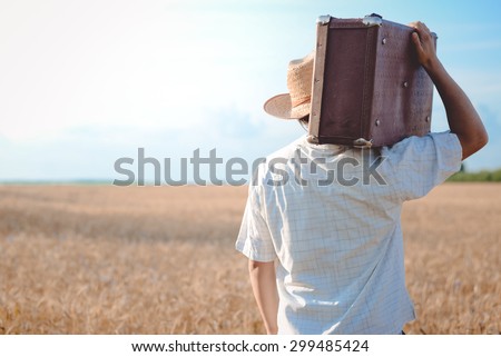 Man in straw hat with a retro suitcase on his shoulder