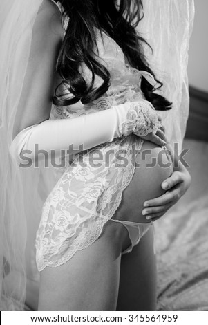 Black and white photography of holding hands on pregnant bare belly beautiful bride wearing sexy lingerie