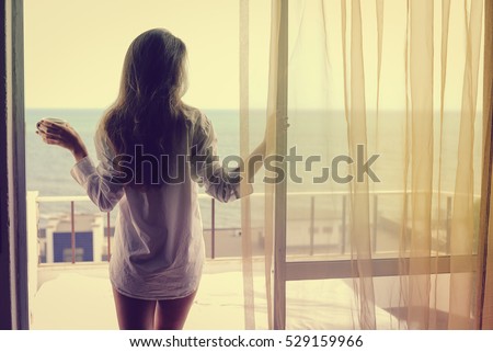 Back view of beautiful woman luxury relaxing enjoying cup of coffee tea on blue sky sea outdoors background
