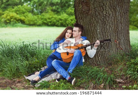 young guy playing guitar for his girlfriend