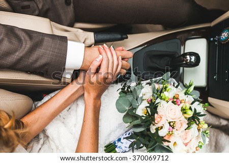 bride and groom holding hands while sitting in the car on the wedding day
