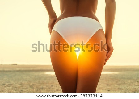 beautiful sexy girl in a swimsuit standing behind at sunset on the beach