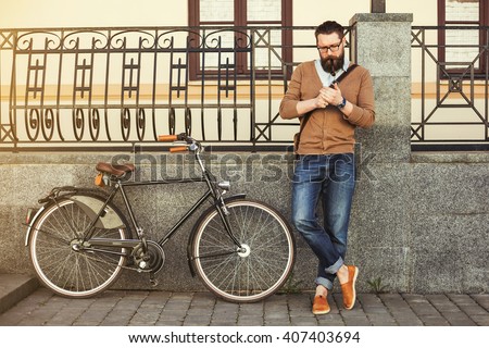 stylish hipster bearded man in the street bike vintage leather handbag, glasses. Vintage style photography, lighting effects. Old european street city