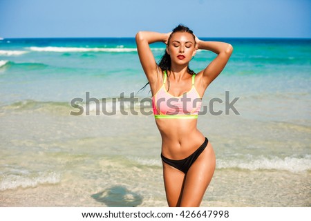 Beautiful sexy amazing woman goes in for sports on the beach, fitness, bikini, perfect tanned body, healthy skin, wet long black hair, hipster, sea, waves, on a tropical holiday vacation