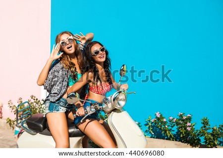 Two cheerful beautiful funny girl hipster, best friends, ride retro scooter, dressed in shorts, T-shirts, sexy bikini, sunglasses, laugh, screaming smile, crazy, fool around, gossiping, party, emotion