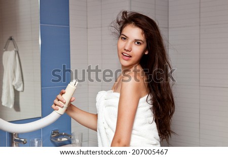 Beautiful young brunette long hair dry hair dryer in the bathroom