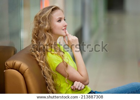 Beautiful girl with long hair sitting on the couch in the store