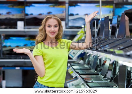 Pretty girl in shop chooses TV and computer