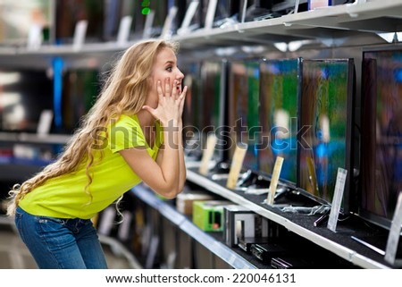 Beautiful girl chooses a television in the store