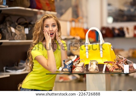 Beautiful surprised girl with yellow bag in a store shopping bags. Shopping
