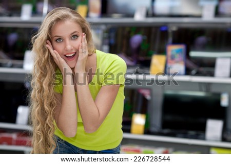 Beautiful young girl with long hair in the store chooses TVs