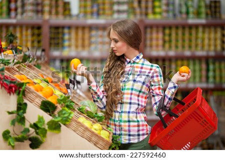 Young girl with red basket in hand selects fruits at the grocery store