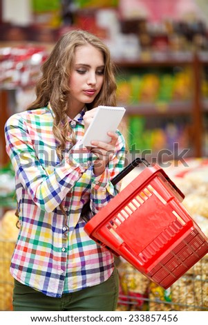 Girl with a notebook and red food baskets at the grocery store