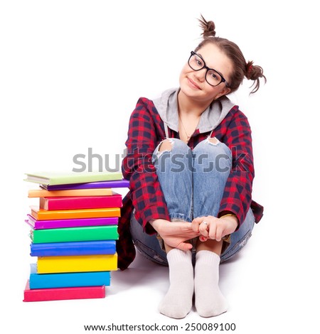 Young student in glasses sits with a stack of books with bright color covers on a white background
