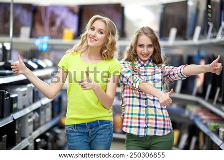 Two young women are choosing a laptop and a television in the electrical shop