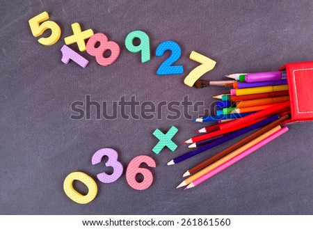Colored pencils and school numbers on a black school board