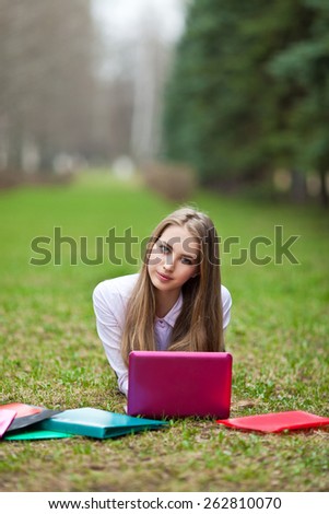 Beautiful student of nature is engaged in a park with books and laptop
