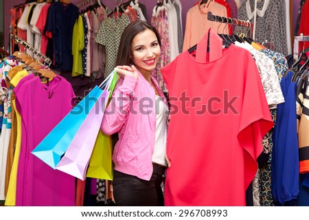 Beautiful girl with colorful packages in hands buys clothes at the mall. The concept of shopping