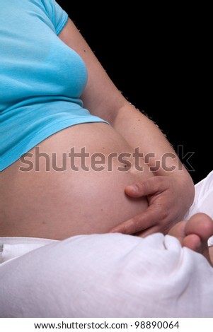 Pregnant woman on dark background with white and blues clothes