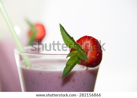 Macro close-up of a strawberry smoothie in a glass decorated with strawberries and mint