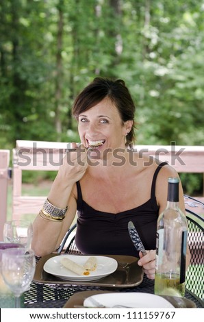 Beautiful woman sitting on a patio eating her lunch