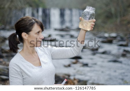 Female researcher checking the water quality from a river