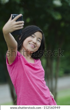 Young Asian girl taking a [self portrait with a cell phone camera