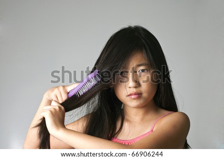 pretty young Chinese girl brushing the tangles out of her hair