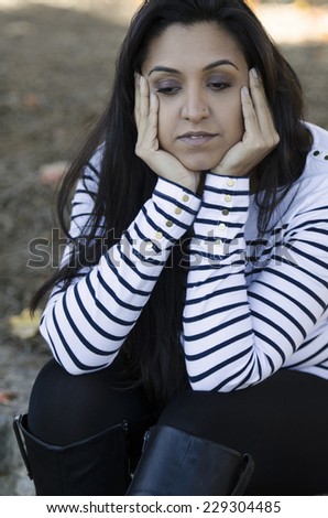 Attractive young Indian woman sitting and lost in her thoughts