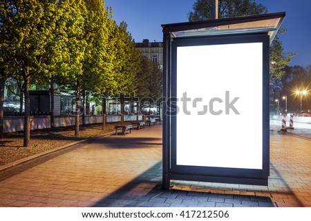 Mock up of blank white vertical light box on a bus stop in a city at night