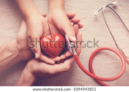 child and adult holding red heart with stethoscope, heart health,  health insurance concept