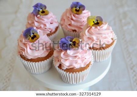 Homemade pink frosting vanilla cupcakes with edible flowers