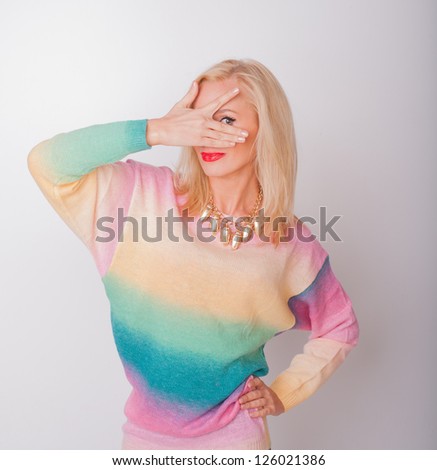 the beautiful girl the blonde in bright clothes with red lips playfully closes a face a hand and spots