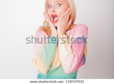 the beautiful fresh blonde the girl in a jacket and on a white background is surprised and very glad